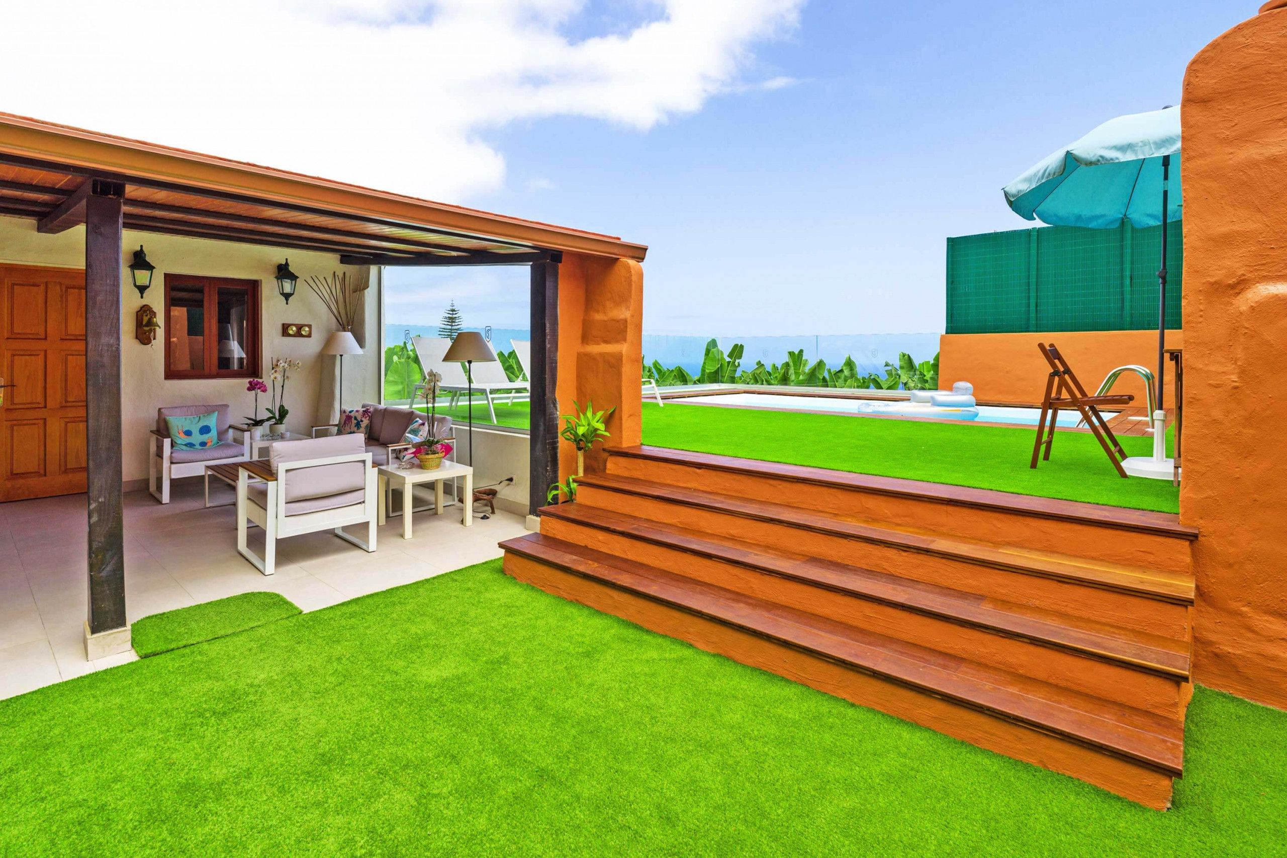 A modern outdoor living area with a patio, seating, and a view of the ocean.