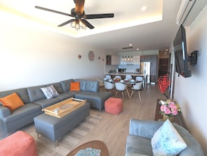 A modern living room with a sectional sofa, a coffee table, and a dining area with chairs and a table.