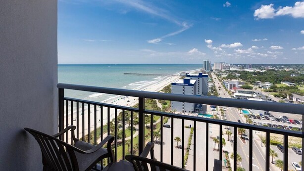 A balcony with a view of the beach and cityscape. - Seaside Splendor 2 Balcony Suite with Sunset Views (Myrtle Beach)