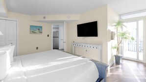 Une chambre d’hôtel équipée d’un lit, d’un téléviseur fixé au mur, d’une fenêtre donnant sur un paysage agréable et d’une porte menant à une petite cuisine.