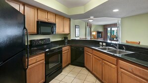 A kitchen with wooden cabinets, a black refrigerator, a microwave, an oven, and a dishwasher.