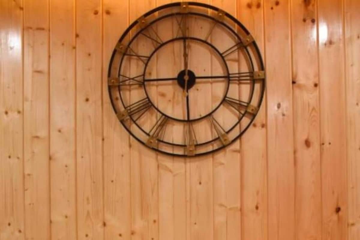 Ein Zimmer mit Holzwänden, einem Bett, Kissen und einer Uhr an der Wand.