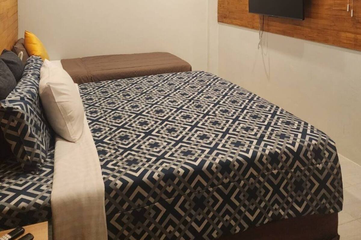 Ein Schlafzimmer mit einem großen Bett, einem Wandfernseher, einer Uhr und einem Deckenventilator.