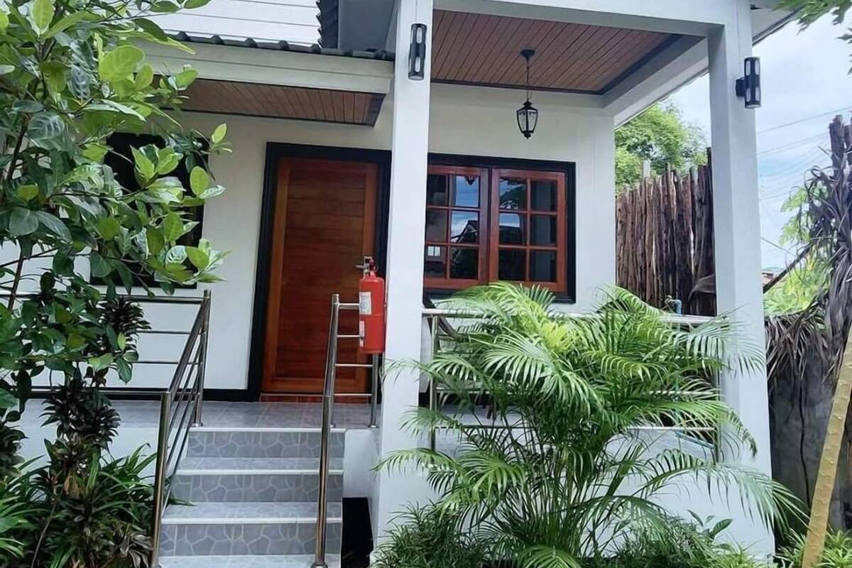Ein zweigeschossiges Haus mit überdachter Veranda, einem Feuerlöscher und einer Treppe, die zum Eingang führt.