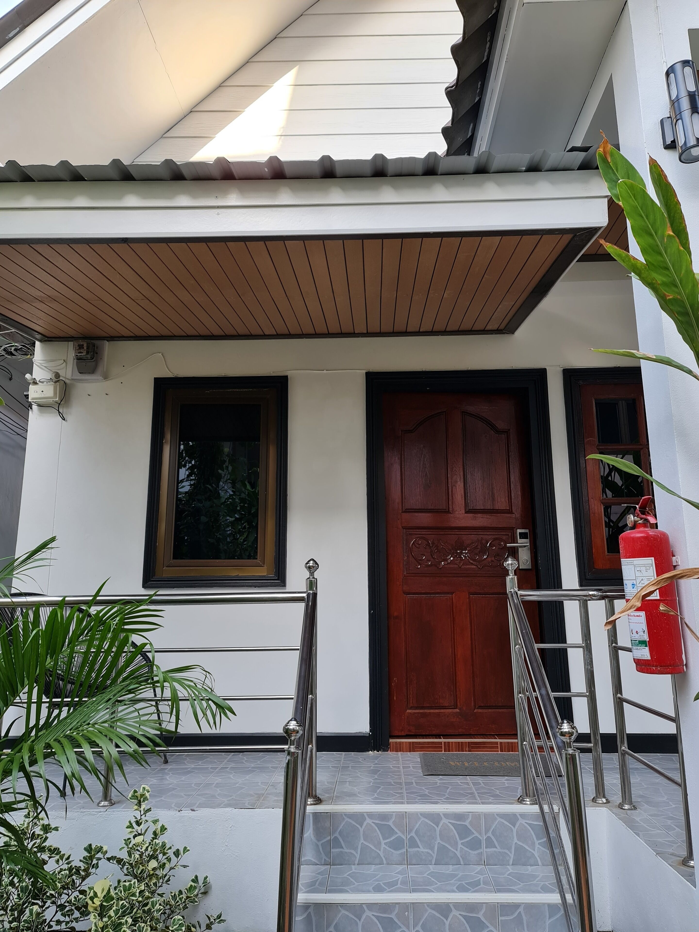 A building entrance with a wooden door, a window, and a fire extinguisher.