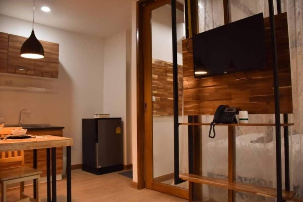Eine moderne Küche mit Holztisch, schwarzem Kühlschrank und einer hängenden Pendelleuchte.