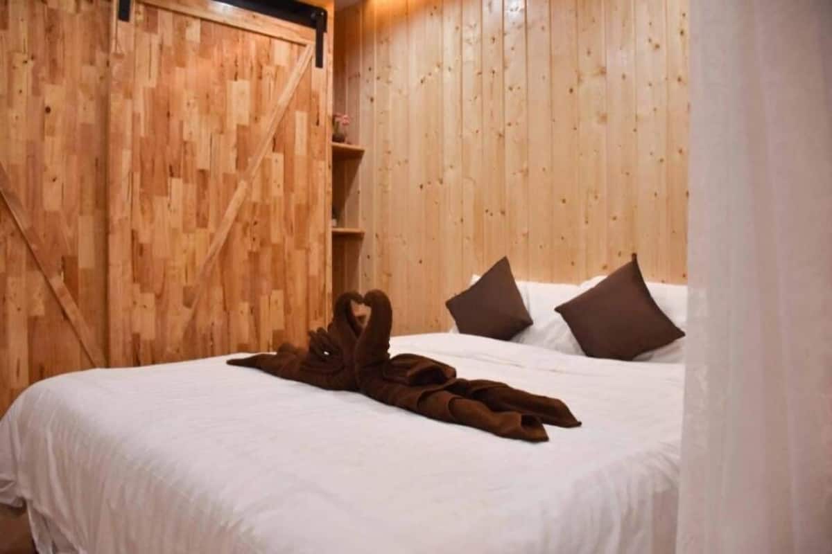 Ein Zimmer mit Holzwänden, einem Bett, Kissen und einer Decke.