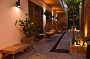 A corridor with hanging chairs, potted plants, and a bench. - Momento Bangtao Beach (Choeng Thale)