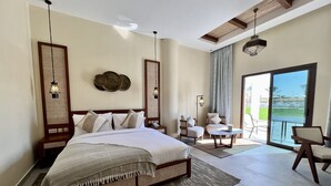 Un dormitorio espacioso con una cama grande, dos sillones, una mesita y un balcón con vistas.