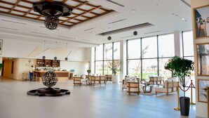 Un hall espacioso con una recepción, zona de estar y grandes ventanales con vistas al exterior.