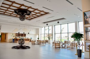 Um hall amplo com balcão de recepção, área de estar e grandes janelas com vista para o exterior.