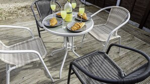 Une table ronde avec une bouteille de PALLADIO, deux assiettes contenant des croissants et trois verres remplis d’une boisson jaune.
