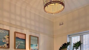 Un salon chaleureux avec un meuble en bois, une table basse en marbre, un canapé beige et une grande fenêtre ornée de plantes.
