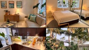Une chambre moderne avec un grand lit, une table de chevet et une commode. La chambre est dotée d’une fenêtre donnant sur des palmiers et une terrasse en bois.
