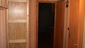 Un pasillo con paredes y puertas de madera que conduce a una habitación oscura.