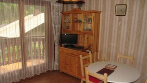 Una habitación acogedora con un armario de madera, un televisor y una mesa de comedor con sillas.