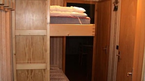 Un pasillo estrecho con una litera y una puerta de madera.