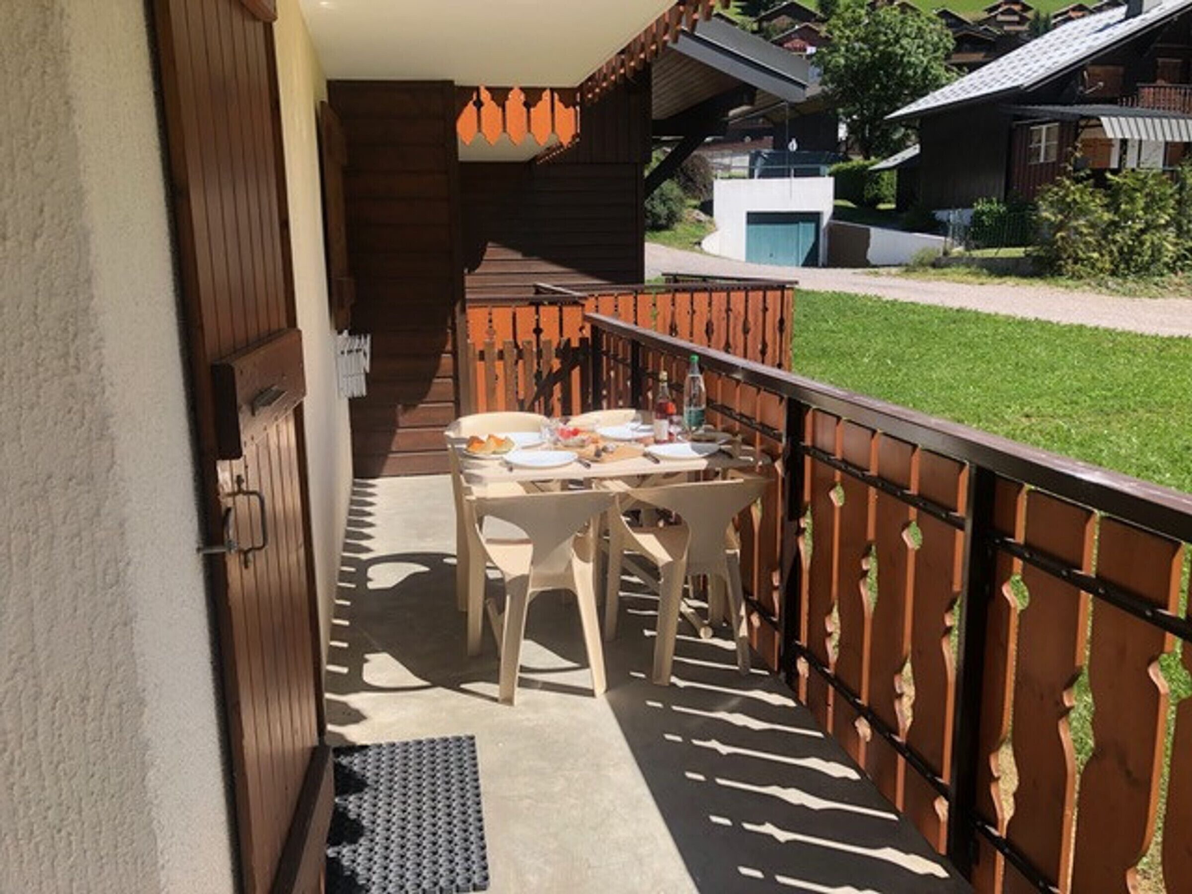Un balcon avec une table dressée pour le dîner, une chaise et un petit tapis.