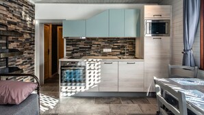 Ett kompakt kök med modern design, med ljusblå skåp, en inbyggd mikrovågsugn och en stänkskydd av sten.