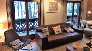 A cozy living room with a brown leather sofa, a black chair, and a wooden ceiling. - Charming chalet 8 pers, fireplace, jacuzzi, parking (Châtel)