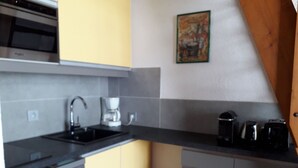 A kitchen with a black countertop, a coffee maker, and a sink.