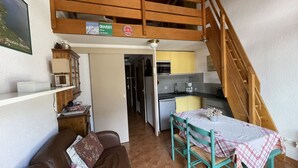 A compact living space with a kitchenette, a dining area, and a loft bedroom.