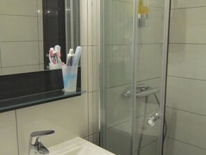 Un bagno con box doccia in vetro, un lavandino bianco e uno specchio sopra il lavandino.