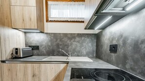 Moderni keittiö, jossa on sisäänrakennettu liesi, pesuallas ja puukaapit.