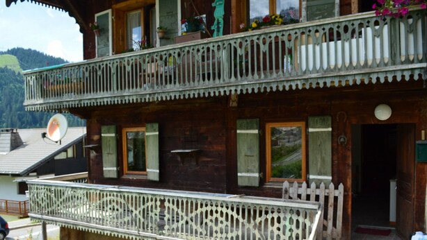 Un chalet en bois doté d’un balcon, d’une antenne parabolique et d’une clôture en bois.