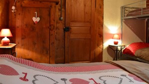 Une pièce en bois avec un lit, un lit superposé et deux lampes.