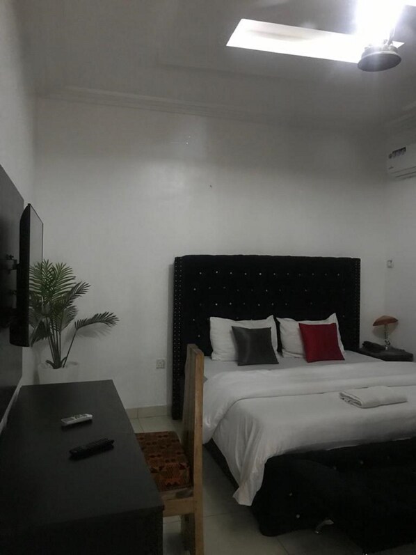 A bedroom with a bed, bedside table, and a TV. - View Point Apartment and Hotel (Lekki)