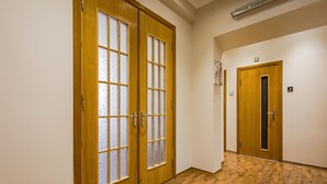 A hallway with wooden flooring and two wooden doors with glass panels.