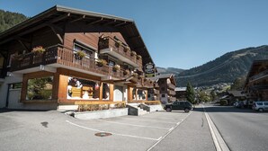 Een traditioneel houten gebouw met een balkon, een bord met 'CREPY SPORTS LOCATION VENUE' en een parkeerplaats ervoor.