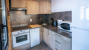 A compact kitchen with wooden cabinets, a built-in oven, a dishwasher, and a microwave. - 3-room apartment for 7 ppl, Châtel, pets allowed (Châtel)