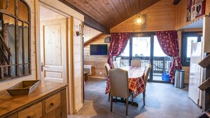 A wooden interior with a dining table and chairs, a kitchen area, and a balcony with a railing. - 3-room apartment for 7 ppl, Châtel, pets allowed (Châtel)