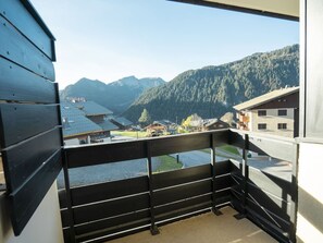 Un balcon offrant une vue sur un village de montagne, des bâtiments en bois et un ciel dégagé.