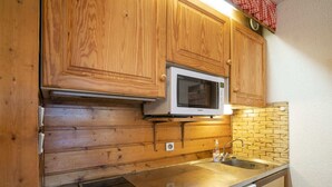 Une cuisine compacte dotée de meubles en bois, d’un four à micro-ondes, d’une plaque de cuisson intégrée et d’un lave-vaisselle.