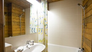 Une salle de bain avec un intérieur en bois, un lavabo blanc, des toilettes et une baignoire.