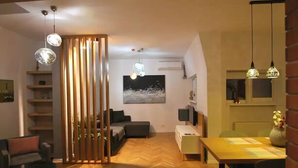 Un salon moderne avec un plancher en bois, un canapé, une table à manger et des luminaires suspendus.