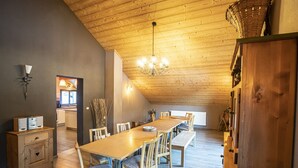 A dining area with a long wooden table and chairs, a chandelier, and a wooden ceiling. - Chalet in Châtel 6 bedrooms, 12 people (Châtel)
