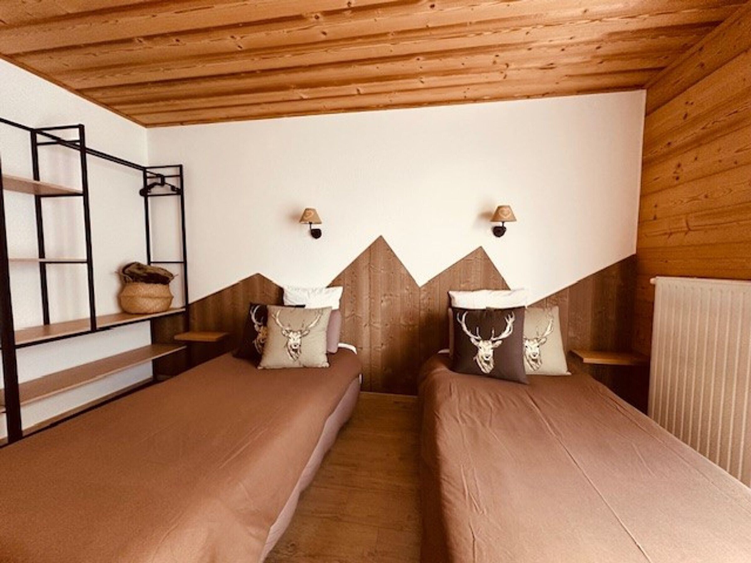 A room with two beds, wooden walls, and a sloped ceiling.