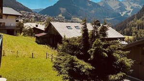 A rural mountain village with traditional houses, a grassy hill, and a valley with mountains in the background. - Chalet in Châtel 6 bedrooms, 12 people (Châtel)