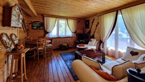 A wooden cabin interior with a sofa, dining table, chairs, a television, and a fireplace. - Charming 2-BR Apt for 6 with Balcony, Near Super-Châtel Lift (Châtel)
