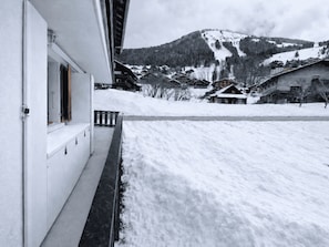 Un paysage enneigĂ© avec un bĂątiment dotĂ© dâun balcon et offrant une vue sur une montagne.
