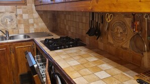 A kitchen with wooden cabinets, a gas stove, a sink, and hanging utensils. - Charming 2-BR Apt for 6 with Balcony, Near Super-Châtel Lift (Châtel)