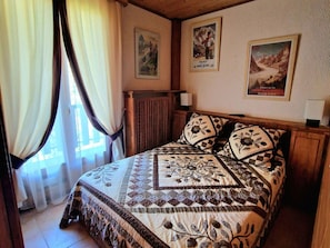Une chambre Ă coucher avec un lit, des rideaux, un radiateur et deux affiches au mur.