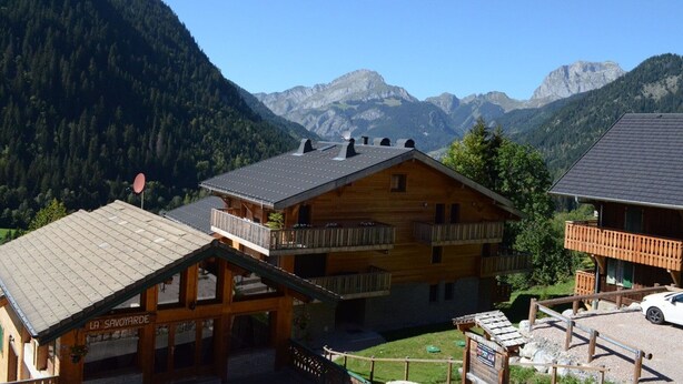 Un chalet en bois doté d’un balcon, entouré de montagnes et surplombant un ciel dégagé.