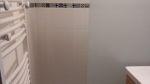 A bathroom with white tiles, a white towel rack, and a patterned tile border. - Studio Cozy in Châtel with Mountain View, Balcony, and Parking (Châtel)