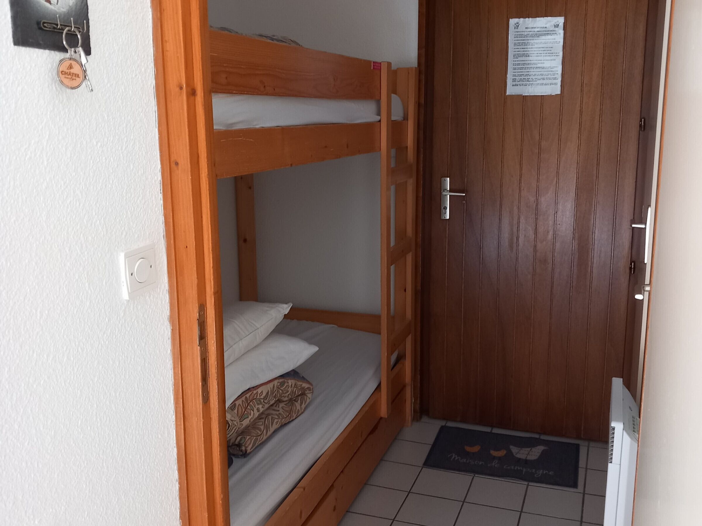 Ein Schlafzimmer mit Etagenbetten, einer Holztür und einer Fußmatte.