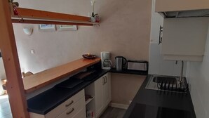 A compact kitchen with a black countertop, white cabinets, a wooden shelf, and a coffee maker. - Studio 4 Pers, Near Chairlift, South Balcony (Châtel)